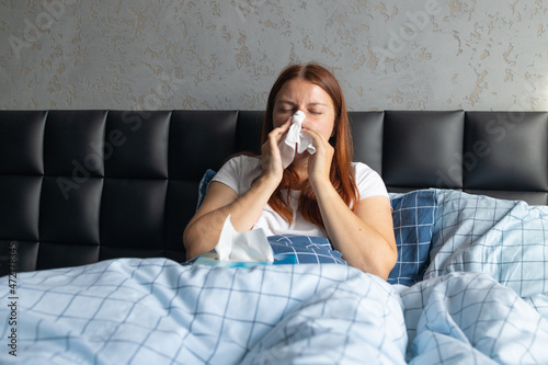 Young woman feeling depressed and stressed with handkerchief runny nose cold infection sitting in the bedroom