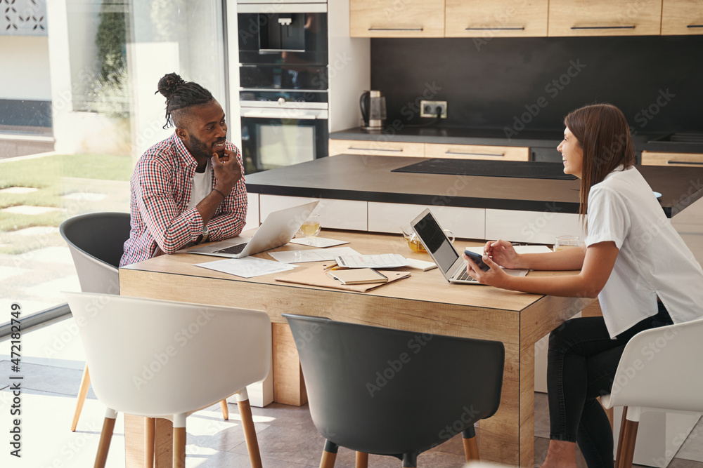 Two telecommuters at desk smiling at each other Two telecommuters at desk smiling at each other