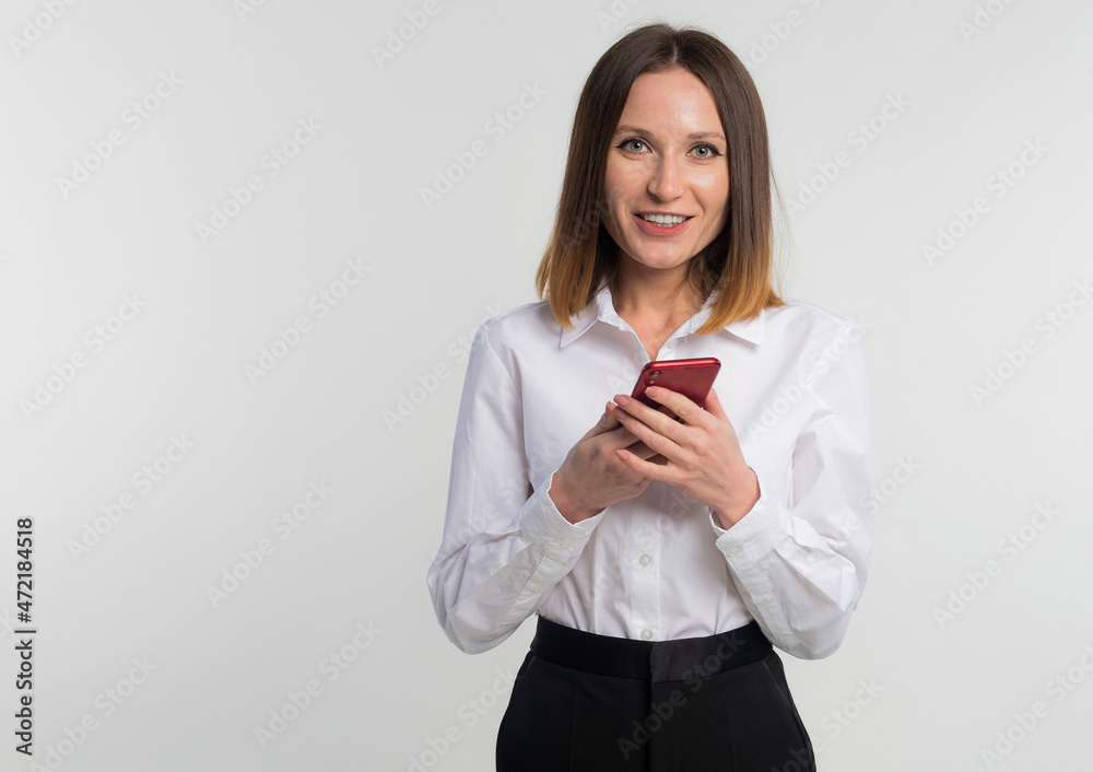 Portrait of pretty, stylish woman in denim outfit holding smart phone in hands, checking email, searching, using internet, chatting with friends standing on grey background, copy space Portrait of pretty, stylish woman in denim outfit holding smart phone in hands, checking email, searching, using internet, chatting with friends standing on grey background, copy space