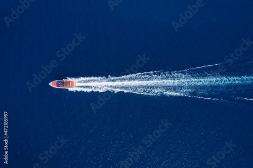 Fast boat at the sea in Bali, Indonesia. Aerial view of luxury floating boat on transparent turquoise water at sunny day. Top view from drone. Seascape with motorboat in bay.