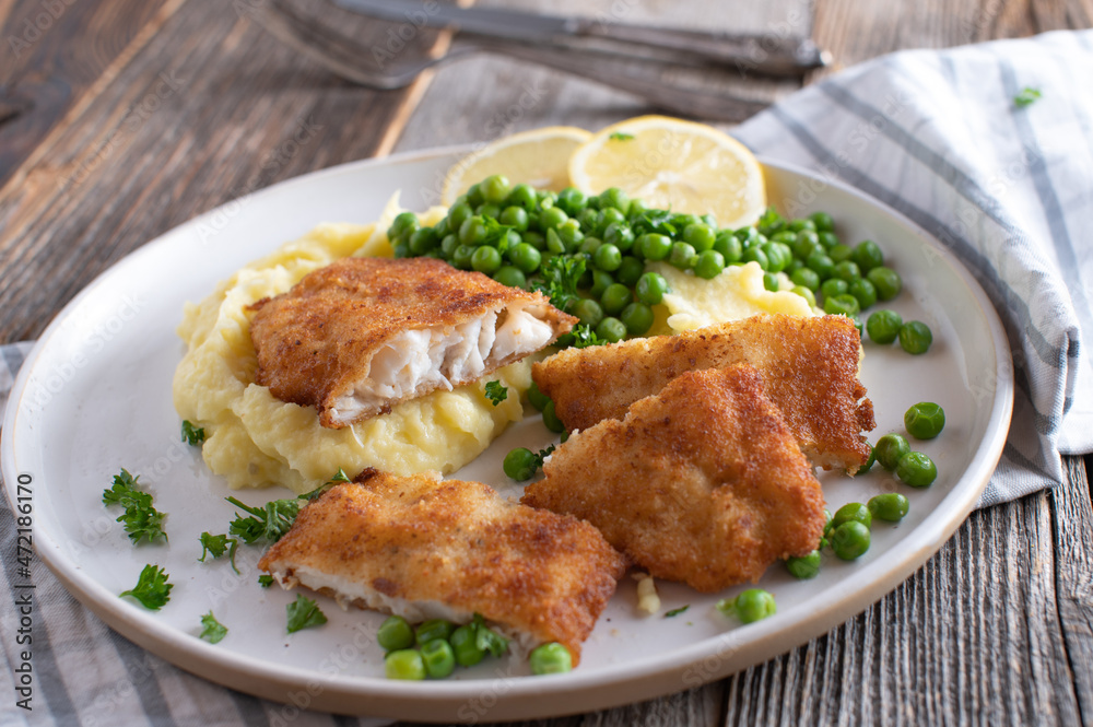 Breaded fish with mashed potatoes and green peas on a plate Breaded fish with mashed potatoes and green peas on a plate