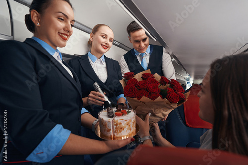 Fényképezés Cheerful cabin crew members handing over presents to female