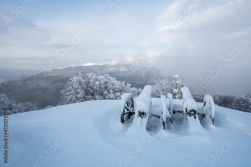 Amazing view with mists over the old cannons at Shipka Monument and the snow-covered mountain slopes of Balkan Mountains at sunrise.
