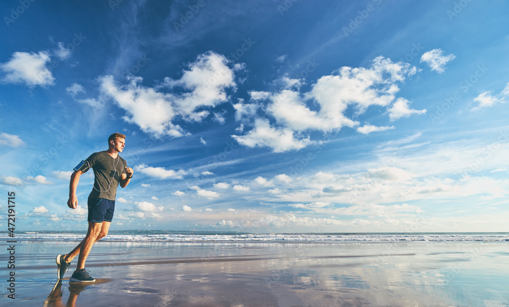 Sports lifestyle. Happy young man in earphones jogging on the sea shore. Sports lifestyle. Happy young man in earphones jogging on the sea shore.