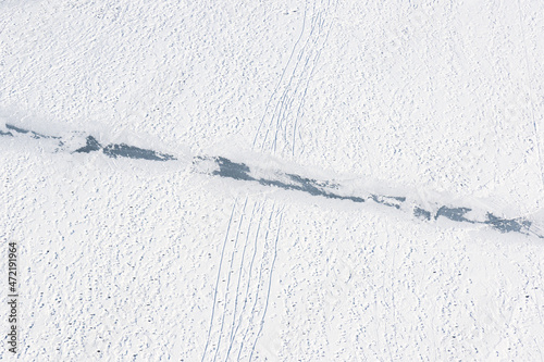 footprints and sledge marks on the snow viewed from drone above