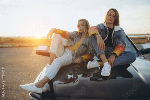 Boy and girl teenagers in fashionable clothes. Friends are posing for the camera. High quality photo