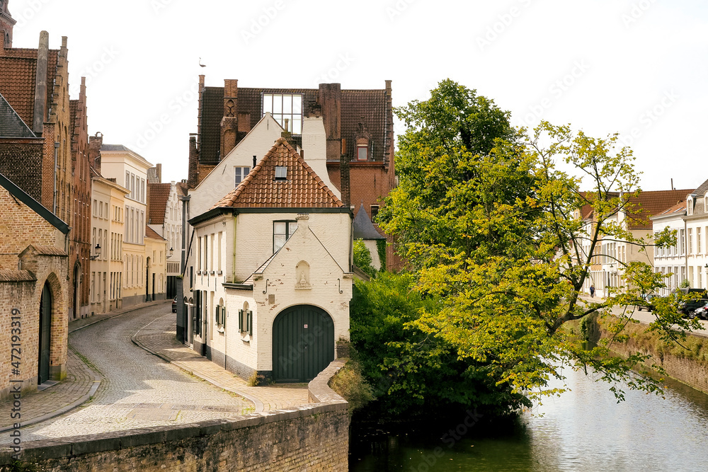 Naklejka premium Paisaje de una casa en un río con un árbol. Brujas, Bélgica.