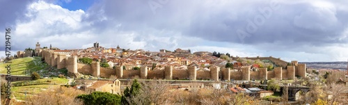 Panoramic view of the Spanish city Avila surrounded by its medieval walls with a dark and cloudy sky on a bad weather day