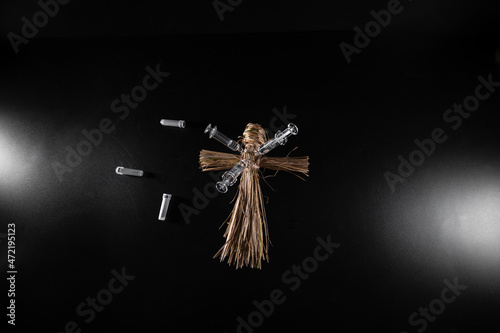 Voodoo doll and syringes on a black background. People management concept. Compulsory vaccination. Drugs and Medicine. Ritual and conspiracy.