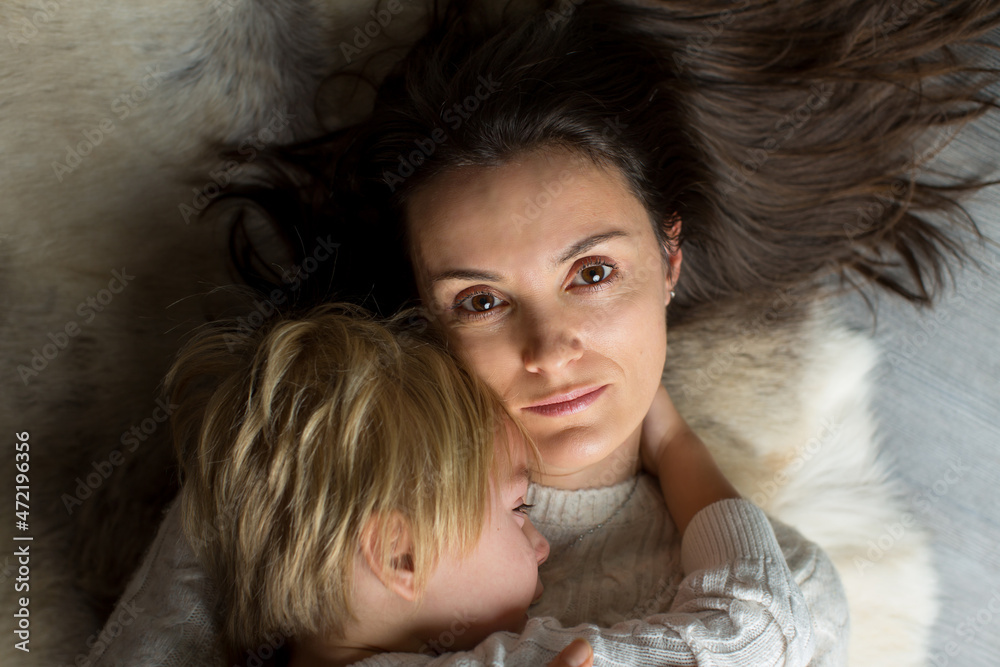 Young mother, holding crying baby, lying on the floor embracing