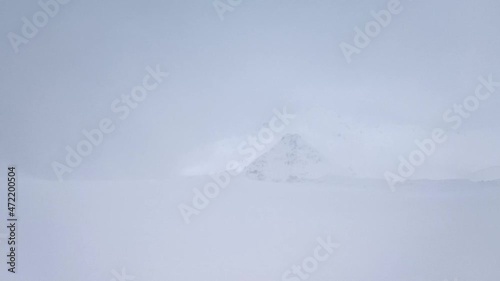 Slow motion. View of the snow-capped mountain peak in a blizzard with a strong wind..