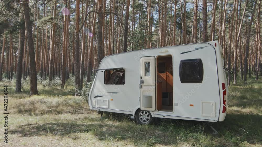 Tracking slowmo of small white camper parked in forest on sunny summer day Tracking slowmo of small white camper parked in forest on sunny summer day