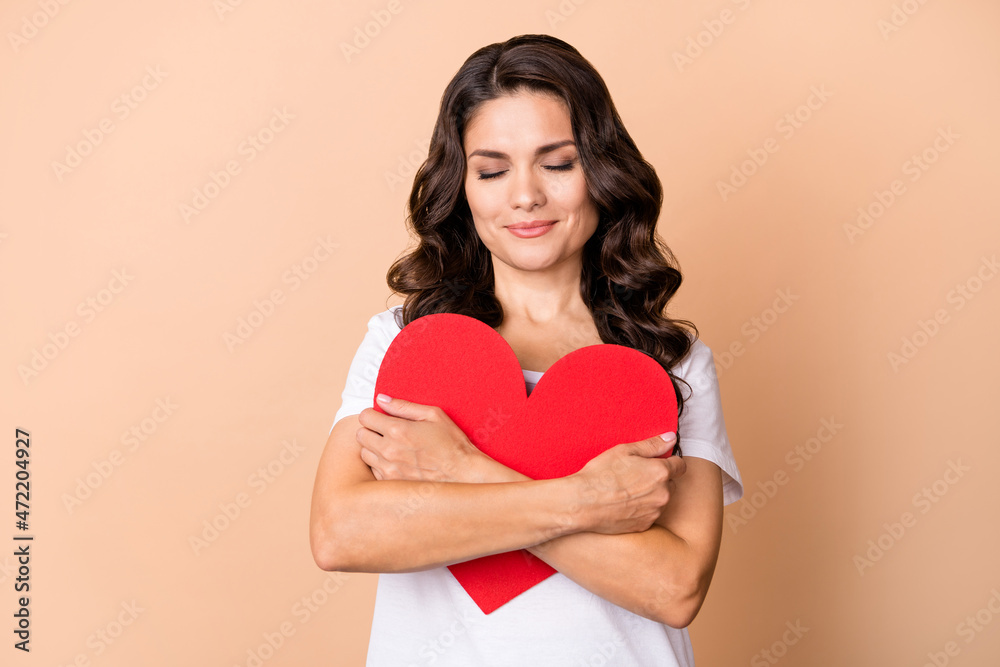Photo of sweet young curly hairdo lady hug postcard wear white t-shirt isolated on beige color background Photo of sweet young curly hairdo lady hug postcard wear white t-shirt isolated on beige color background
