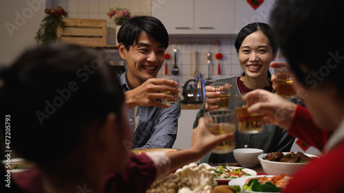 selective focus of happy young asian couple drinking toast with tea to their family at chinese lunar new year reunion dinner at home