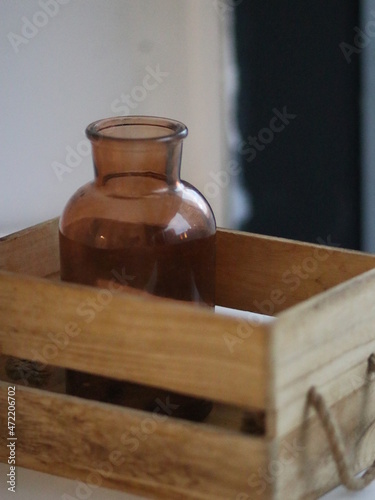 Glass brown jar in a wooden box on the windowsill