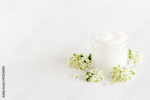 White blossoms flowers with skin cream in glass jar