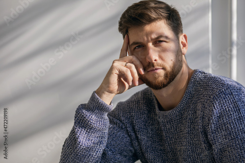 фотографія A man with a sad look and shadows on his face looks sadly at the camera