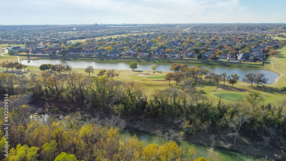Top view country club golf course and lakeside residential houses near nature park with fall foliage in Carrollton, Texas, USA