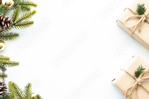 Beautiful Christmas background with two gift boxes, decorate with pine branches and golden balls over white background. Top view with copy space, flay lay.