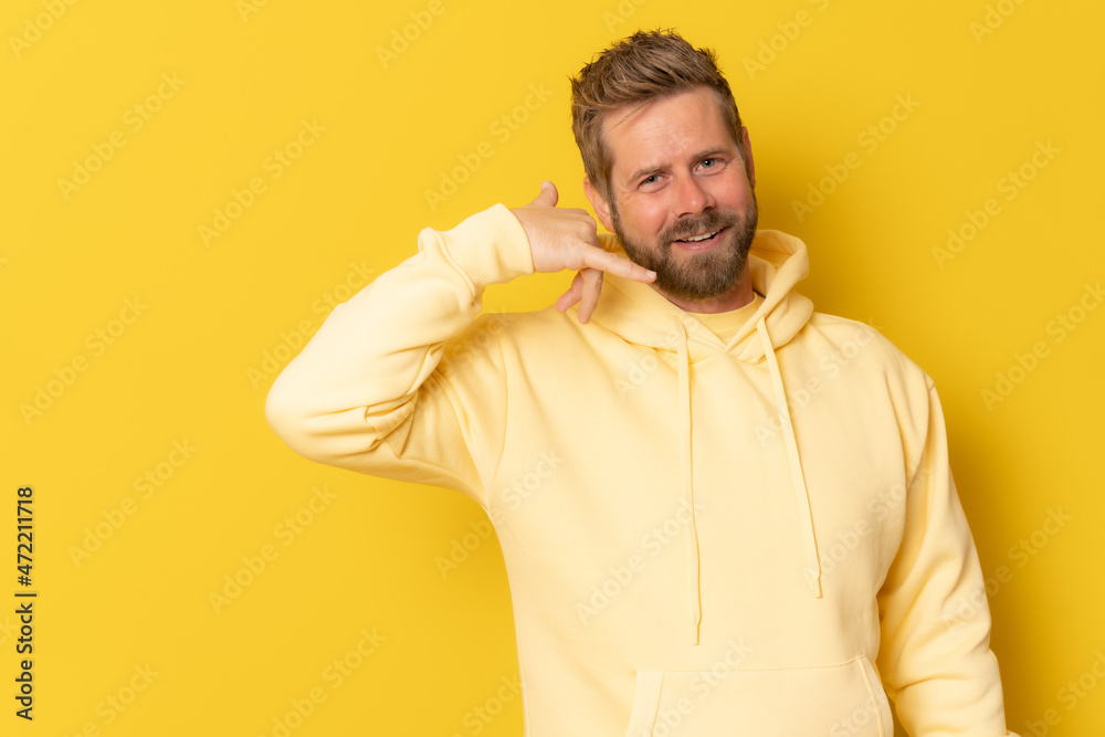 Young man over isolated yellow background making phone gesture. Call me back sign