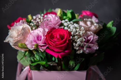 Beautiful bouquet of colorful rose flowers on a black background. Festive flowers concept with copy space. Flowers on a black background. Bouquet of fresh roses  freesias  eustoma and others.