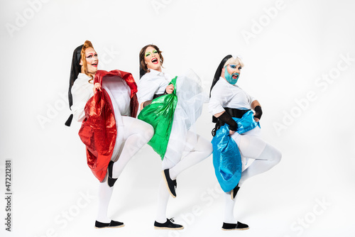 Happy drag queens in cancan dancing by white background photo