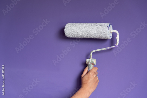 Woman hand holding painting roller just before touching wall