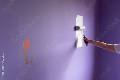 Woman arm painting with roller on tulip stencil wall