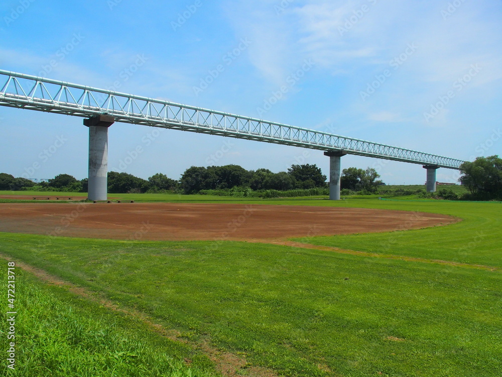 梅雨晴れの平日の江戸川河川敷の整地された野球場とガス導管のある風景 梅雨晴れの平日の江戸川河川敷の整地された野球場とガス導管のある風景