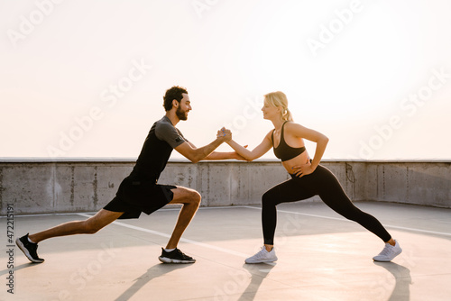 Young man and woman doing exercise while working out together on parking