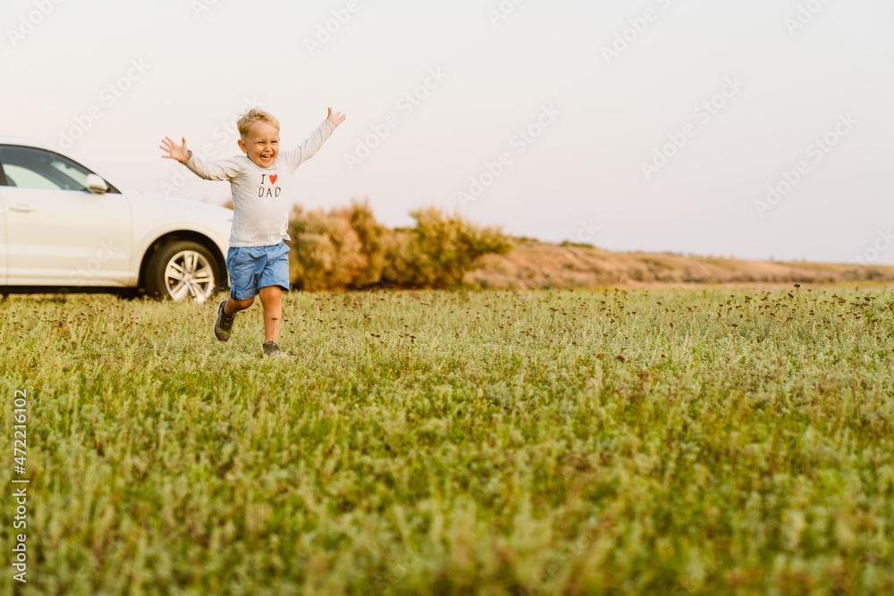 Blonde white boy smiling while running with hands up on field Blonde white boy smiling while running with hands up on field