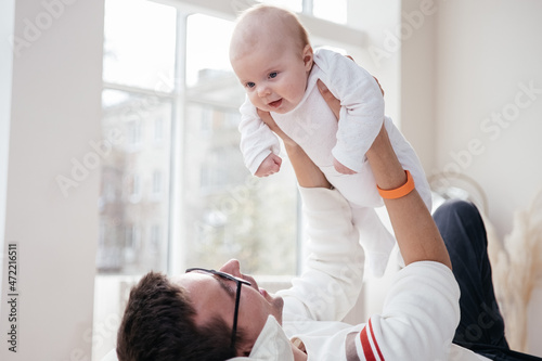 Father laying on the bed with his little infant baby. Family together at home. Single dad. Parental leave