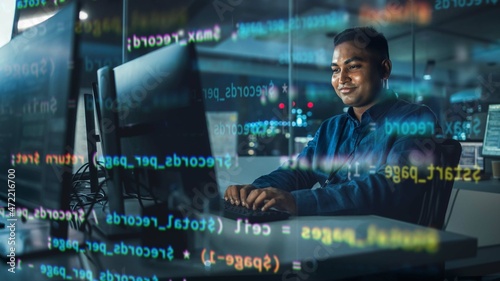 Concept Shot with Visualisation of Running Computer Code on Foreground. Portrait of Handsome Indian Man in Working on Computer at Night in Office. Digital Entrepreneur Creating Modern Software.