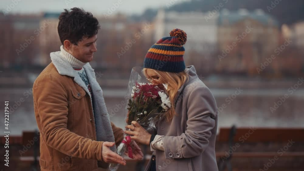 Young man giving bloom flower bouquet to woman on Valentine day, first date. Valentine day concept, love and funny advertizing