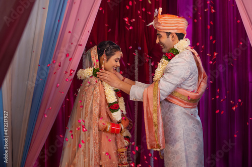 Couple performing Jaimala in mandap during their wedding photo