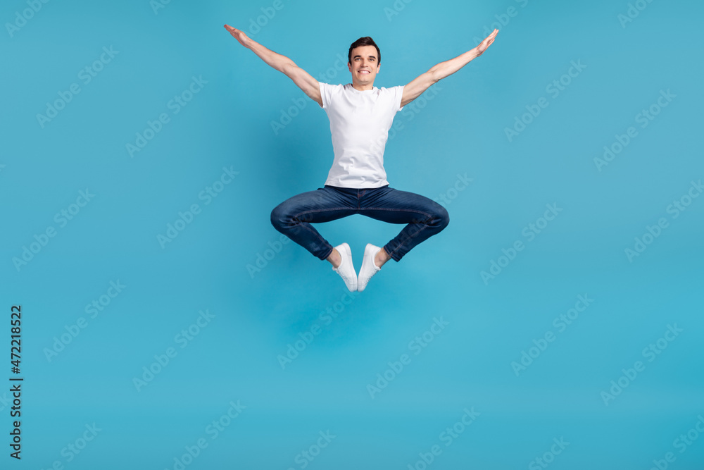 Full size photo of young excited man have fun jump up air fly energetic isolated over blue color background
