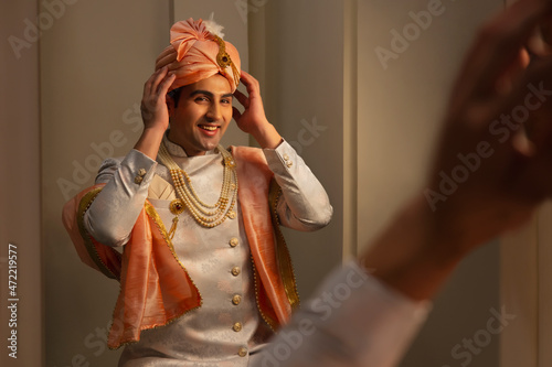 Reflection of a groom in the mirror wearing pagdi during wedding ceremony  photo