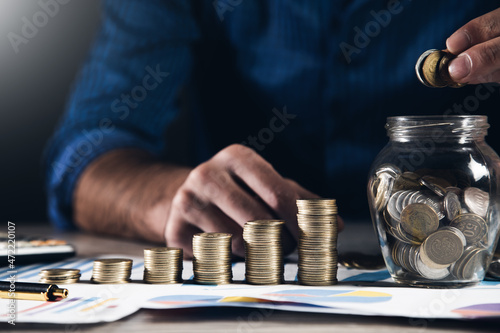 businessman hand holding coins putting in jar © ARAMYAN