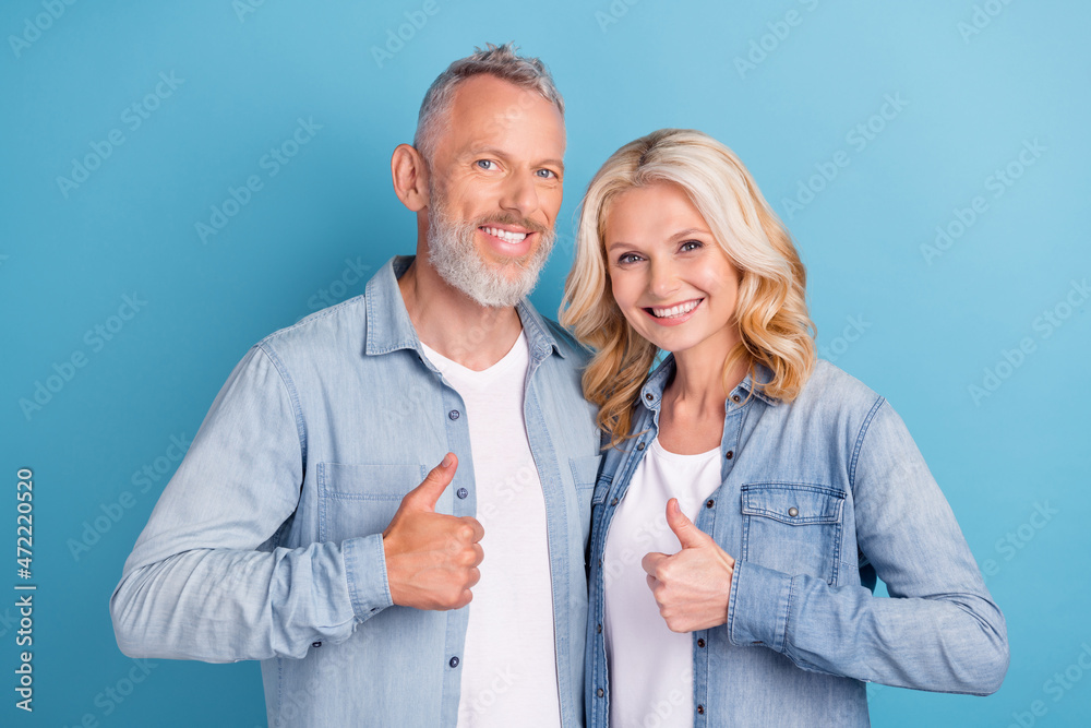 Photo of mature couple happy positive smile cuddle show thumbs-up like fine feedback isolated over blue color background Photo of mature couple happy positive smile cuddle show thumbs-up like fine feedback isolated over blue color background