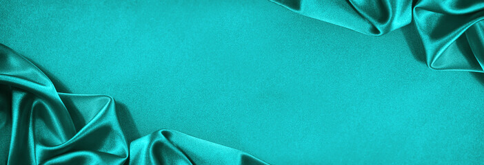 Beautiful blue green silk satin. Soft folds on shiny fabric. Luxury turquoise background with copy space for design. Wide banner. Flat lay, top view. Birthday, Christmas, Valentine, Valentine's Day.