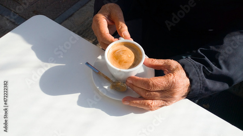 an older man has a cup of coffe latte at a white table