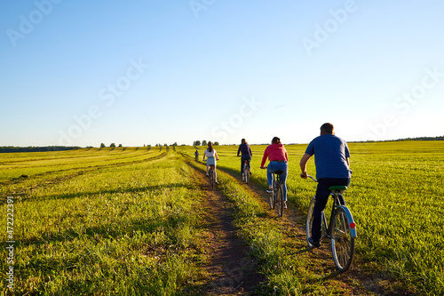 Cyclist on a dirt land road in a field at a summer day or evening