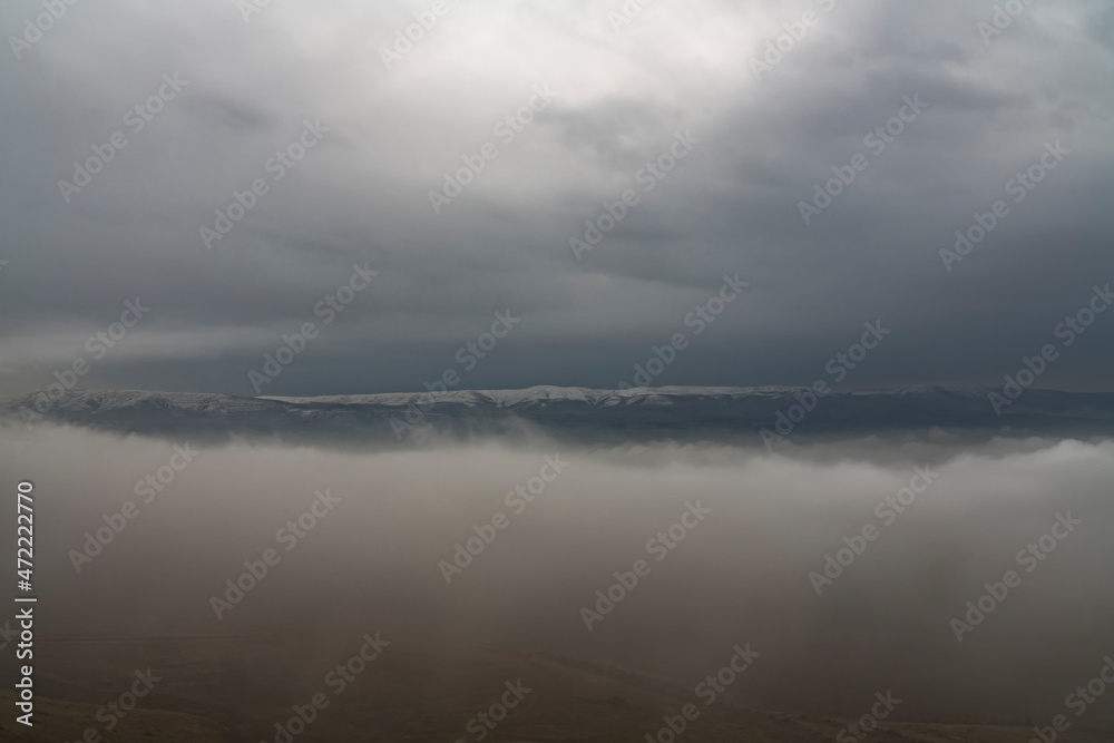 Beautiful winter landscape. The huge clouds above the mountains. Foggy weather