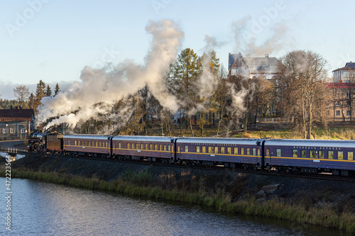 Russia, Karelia, Sortavala, 08.09.2021. Retro train named the Ruskeala Express in the direction of Sortavala - Ruskeala Mountain Park, on the railway near the lake and lets smoke out of the chimney.