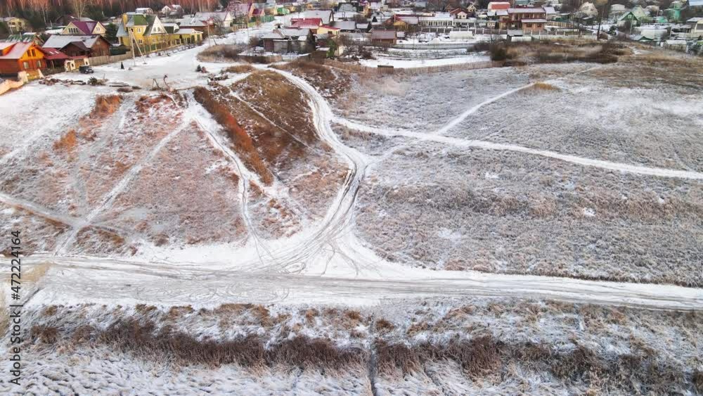 Field, slope and village under the snow in the orange light of the sun. In winter, at sunset, in the evening. Screensaver, footage, nature for intro, background, titles. UHD 4K.