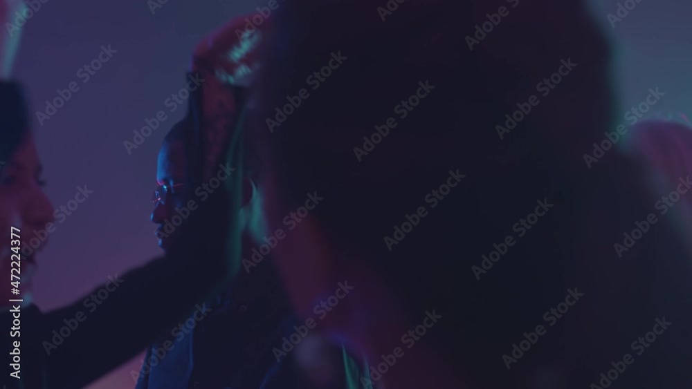 Medium close up with slowmo of multiethnic young men and women dancing at party in night club on neon lights Medium close up with slowmo of multiethnic young men and women dancing at party in night club on neon lights