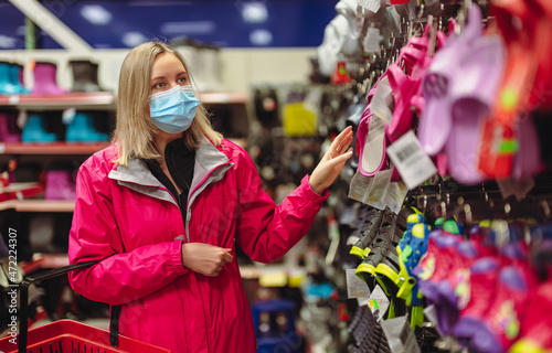 Woman in medical mask is choosing flip-flops.
