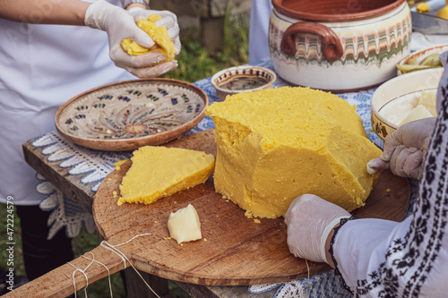 woman's hands cut polenta on the table with Romanian ornaments