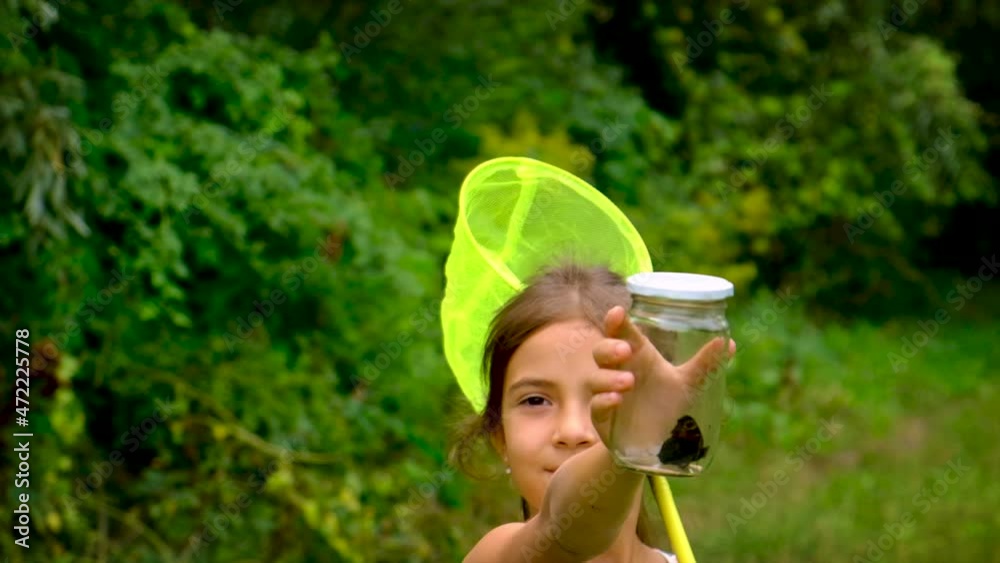 A child girl catches butterflies with a butterfly net. Selective focus. A child girl catches butterflies with a butterfly net. Selective focus.