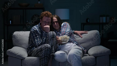 Couple on a sofa at night watching a scary movie